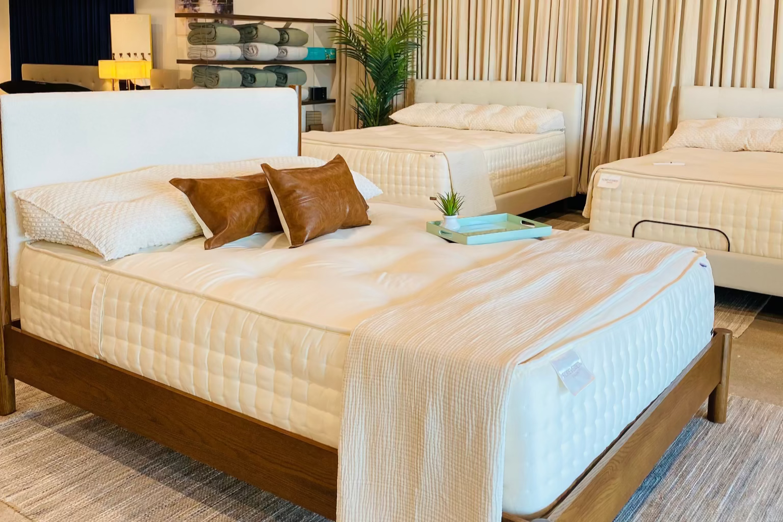 Bedroom setting with multiple beds and a chandelier in a showroom.
